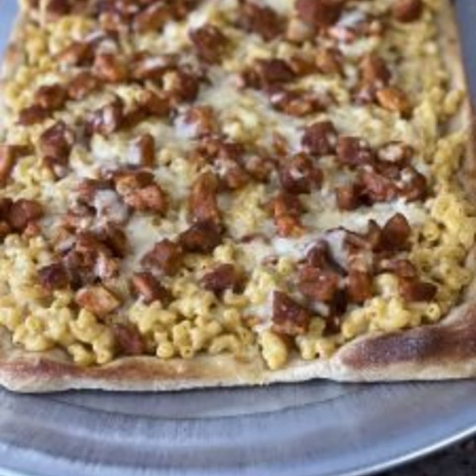 Mangia Pizza's square pizza topped with macaroni and cheese and chicken pieces on a metal tray.