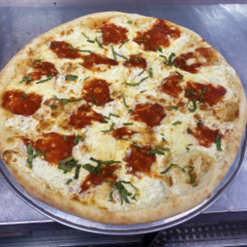 Mangia Pizza's white pizza with dollops of red sauce and fresh basil on a metal tray.